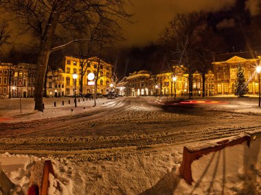 Den Haag, Hollanda - 20 Aralık 2009: Den Haag 'da gece karlı bir sahne. Binalar sıcak bir ışıltıyla aydınlatılır. Caddede trafik ışığı izleri var..