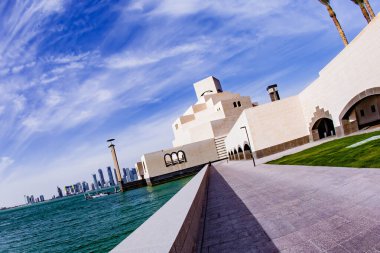 Doha, Katar - 27 Ocak 2010: Ziyaretçiler Doha 'daki rıhtımda geziniyorlar ve sakin bir sahil zeminine karşı çarpıcı modern mimariye tanık oluyorlar.
