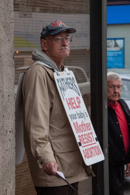 Vancouver, Kanada - 30 Ekim 2009: Vancouver 'da bir sokakta duran bir adam, babaları kürtaja direnen annelere yardım etmeye çağıran bir tabela takıyor.