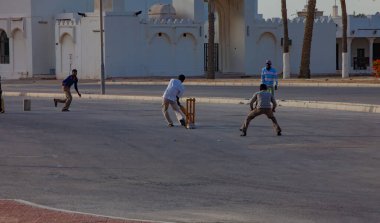Doha, Katar - 26 Ocak 2010: İnsanlar Doha Katar 'da sakin bir sokakta kriket oynuyorlar ve güneş batarken maçın keyfini çıkarıyorlar.