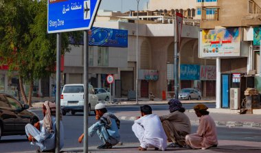 Doha, Katar - 26 Ocak 2010: Katar 'ın hareketli ortamında günlük yaşamı sergileyen Doha sokaklarında bir grup işçi sıcak öğleden sonra mola verdi.
