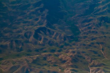 Parlak mavi gökyüzünün altındaki dalgalı dağ ve vadilerin nefes kesici manzarası doğanın güzelliğini ve huzurunu gözler önüne seriyor..