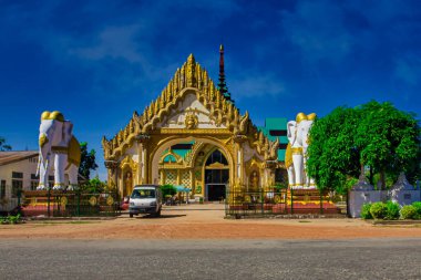 Bago, Myanmar - 02 Aralık 2012: Myanmar 'da açık mavi gökyüzünün altında heykeli olan altın balo tapınağı. Ziyaretçiler mimariye hayran..