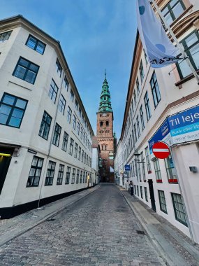 Kopenhag, Danimarka - 24 Temmuz 2023: Kopenhag 'da dar bir cadde tarihi evlerle çevrili Nikolaj Kilisesi kulesine bir göz attı