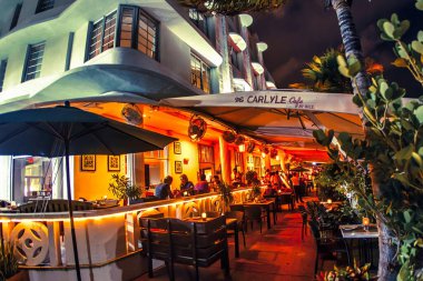 Miami, ABD - Ekim 06 2011: Konuklar Miami Beach 'te canlı bir atmosferin arka planına karşı sıcak ışıklarla aydınlatılmış bir kafede açık hava yemeğinin keyfini çıkarıyorlar.
