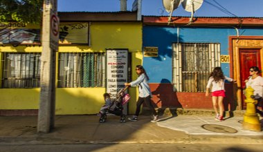 Santiago, Şili - 17 Kasım 2014: Yayalar sıcak bir Kasım gününde yürürken Şili 'de küçük renkli evler cadde boyunca sıralanır.