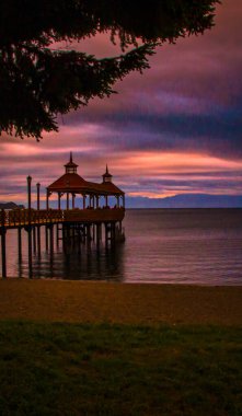 Puerto Varas, Şili - 11 Kasım 2014: Puerto Varas Şili üzerinde güzel bir günbatımı sakin su kıyısında manzaralı bir ahşap iskele vurguluyor