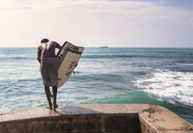 Honolulu, ABD, 07 Aralık 2012: Bir kişi Honolulu 'daki Waikiki Sahili' nde sörf yapmaya hazırlanıyor. Gün boyunca sakin suların ve güzel gökyüzünün tadını çıkarıyor..