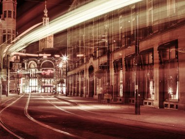 Lahey, Hollanda - Ekim 09 2008: Geceleyin den haag 'da tramvay rayları ve hafif patikaları olan cadde. Arka planda bir kafe ve saat kulesi görünüyor..