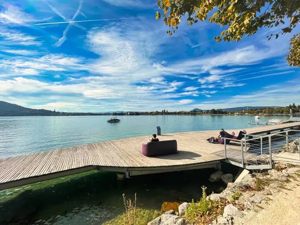 Annecy, Fransa - 15 Ekim 2021: Ziyaretçiler Fransa 'daki Annecy Gölü' ndeki ahşap bir tahta kaldırımda güneşin ve manzaranın keyfini çıkarıyorlar