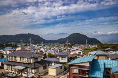 Yudanaka, Japonya - 24 Ekim 2017: Yudanaka Nagano 'da dağları ve arka planda açık bir gökyüzü olan geleneksel evleri gösteren güzel manzara.
