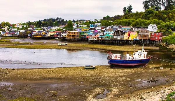 Castro, Şili - 09 Kasım 2014: Castro kıyı şeridi boyunca canlı ahşap evler içeriyor ve alçak gelgit sırasında karada dinlenen bir tekne tarafından tamamlanıyor..