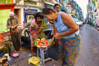 Yangon, Myanmar - 4 Aralık 2012: Yerel halk, Yangon 'un hareketli sokaklarında güpegündüz taze karpuz satan bir sokak satıcısının etrafında toplandı.