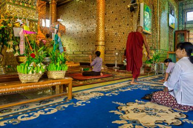 Yangon, Myanmar - 03 Aralık 2012: Bir keşiş Yangon Myanmar 'da güzel dekore edilmiş bir manastırda yürürken dindarlar namaz kılıyor.