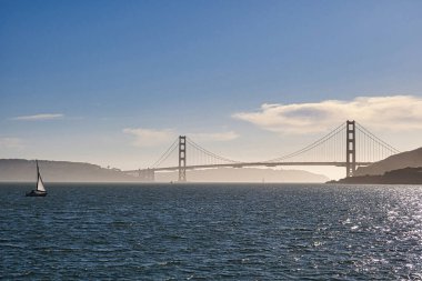 San Francisco, ABD - 13 Şubat 2020: Sausalito 'nun arka planına karşı sisli Golden Gate Köprüsü ile yelkenli teknesi körfezde süzülüyor.