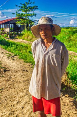Bago, Myanmar - Aralık 03 2012: Myanmars kırsalında açık renk tişört ve şortla poz veren yerel bir adam açık gökyüzü altında yemyeşil bir arazide.