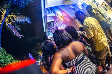 Miami, ABD - Ekim 06 2011: Arkadaş grupları Miami Plajı 'nda canlı ışıklar altında ve palmiye ağaçları altında neşeli gece hayatı ruhunu yakalayan bir akşamın keyfini çıkarıyorlar.