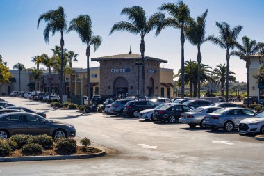 Oxnard, ABD - 20 Şubat 2020: Oxnard California 'da açık gökyüzü altında palmiye ağaçları bulunan bir alışveriş merkezinin yanında çeşitli araçlarla dolu yoğun bir otopark.