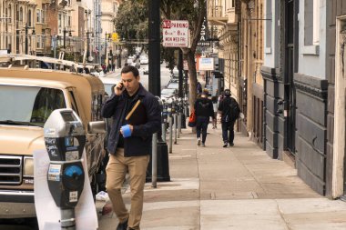 San Francisco, ABD - 13 Şubat 2020: Bir adam San Francisco 'da kaldırımda yürürken diğerleri geçerken cep telefonuyla arama yapıyor.