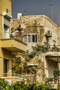 Tel Aviv, İsrail - 11 Kasım 2010: Bir kişi Tel Aviv 'de bir balkondan aşağı eğiliyor ve öğleden sonra şehrin sıcak havasının ve canlı atmosferinin tadını çıkarıyor.