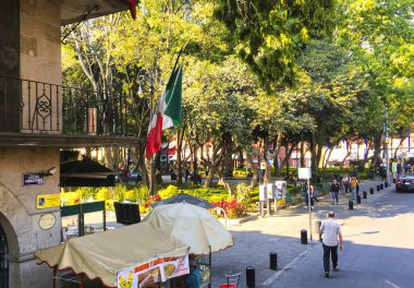 Mexico City, Mexico - 02 Şubat 2017: Meksika 'da Meksika bayrağı dalgalanırken, bir içecek tezgahı müşterileri bir koloni binasının önüne çekiyor