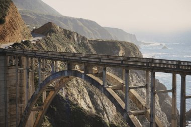 Big Sur, ABD - 19 Şubat 2020: Bixby Köprüsü 'nün çarpıcı sahil kayalıkları ve Kaliforniya Büyük Sur' daki okyanus dalgalarıyla çevrili geniş manzarası