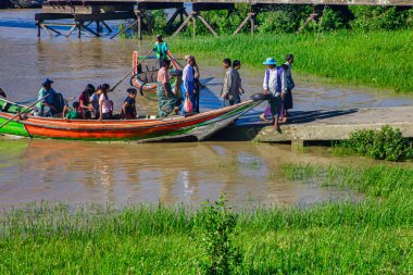 Yangon, Myanmar - 03 Aralık 2012: Yerel halk güneşli bir günde Yangon Myanmar 'daki sakin bir nehir kıyısında renkli botlara binmek için toplandı..