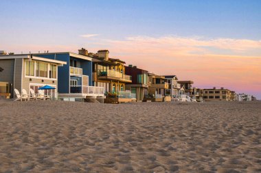 Oxnard, Amerika Birleşik Devletleri - 21 Şubat 2020: Ahşap kiralama şirketleri günbatımında kumlu Oxnard sahilinde gökyüzünü boyuyor ve sakin bir atmosfer yaratıyor.