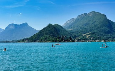 Talloires, Fransa - 25 Haziran 2023: İnsanlar dağlarla ve duingt şatosuyla ilhak gölünün suyunun tadını çıkarıyorlar