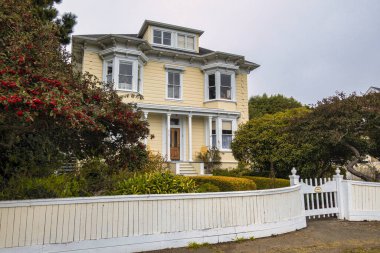 Mendocino, ABD - 16 Şubat 2020: Idyllic beyaz ahşap şehir evi, sakin bir şubat gününde, yemyeşil ile çevrili, gururla duruyor.