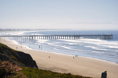 Pismo Beach, ABD - 19 Şubat 2020: Uçurum perspektifi Pismo Sahili rıhtımında turistlerin Şubat ayında kıyı atmosferini yakaladığını gösteriyor.