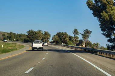 Santa Barbara, ABD - 20 Şubat 2020: Güneşli bir günde Santa Barbara California 'da palmiye ağaçları ve elektrikli araçlarla çevrili manzaralı bir yolculuğun tadını çıkarmak