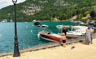 Talloires, Fransa - 20 Haziran 2023: Ek bina gölü kıyısındaki rıhtımda yürüyen ziyaretçiler