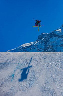 Tignes, Fransa - 12 Mart 2010: Bir kayakçı X Oyunları sırasında açık bir gökyüzü altında karlı yamaçlar ve dağlar üzerinde süzülüyor.