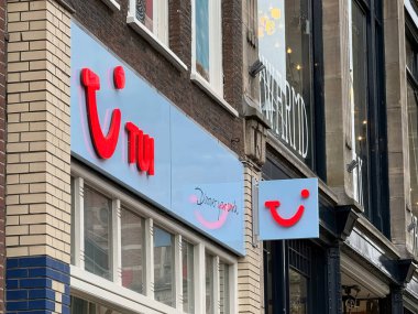 Hollanda, den haag - 18 Ekim 2024: TUI için parlak renkli tabelalar Den Haag 'da markasını gösteriyor. Dükkanlar yayalarla dolu kalabalık bir caddede bulunuyor.