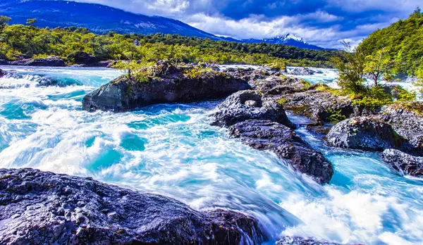 Puerto Varas, Şili - 10 Kasım 2014: Puerto Varas Şili yakınlarındaki Petrohue nehrinde kayaların üzerinden taşan vahşi sular çarpıcı dağ manzaralarıyla çevrilidir..