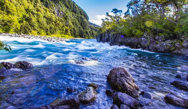 Vahşi Petrohue Nehri, Puerto Varas Şili 'deki yemyeşil dağlar ve ağaçlarla çevrili kayaların üzerinde dramatik bir şekilde çağlıyor..