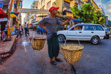 Yangon, Myanmar - 4 Aralık 2012: Bir satıcı Yangon caddesinde sepet taşıyor ve Myanmars 'ın hareketli atmosferinde yerel ticaret ve günlük hayatı gözler önüne seriyor.
