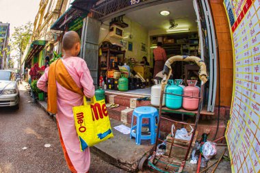 Yangon, Myanmar - 4 Aralık 2012: Yangon Myanmar 'da yerel satıcılarla çatışan bir pazarı ziyaret ederken genç bir keşiş renkli bir çanta taşıyor.