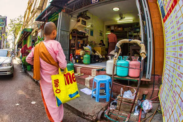 Yangon, Myanmar - 4 Aralık 2012: Yangon Myanmar 'da yerel satıcılarla çatışan bir pazarı ziyaret ederken genç bir keşiş renkli bir çanta taşıyor.