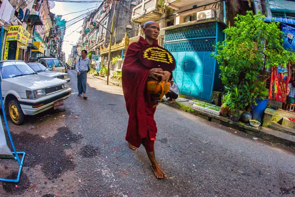 Yangon, Myanmar - 4 Aralık 2012: Yangon 'da bir keşiş hareketli bir cadde boyunca çıplak ayakla yürüyor..
