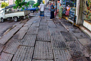 Yangon, Myanmar - 4 Aralık 2012: İnsanlar Yangon Myanmar 'da hareketli bir öğleden sonra caddelerde mal dolu dükkanlarla birlikte düz kaldırımlar boyunca yürüyorlar.