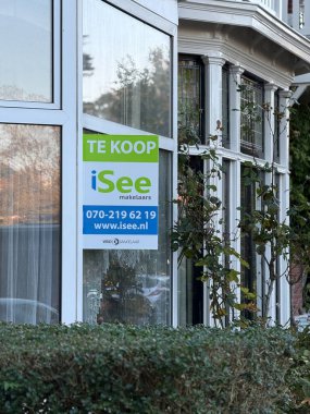 Den Haag, Hollanda - 24 Ekim 2024: Potansiyel alıcıları soru sormaya davet eden bir mülkün reklamını yapan bir pencerede belirgin bir tabela asılı.