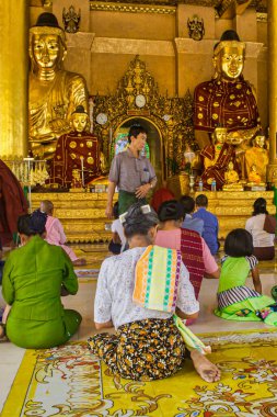 Yangon, Myanmar - 4 Aralık 2012: İnsanlar Yangon tapınağında diz çöküp dingin bir ortamda büyük altın heykellerin yanında dua ediyorlar..