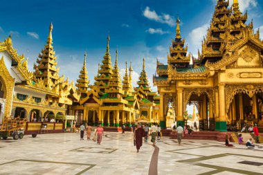 Yangon, Myanmar - 4 Aralık 2012: Ziyaretçiler Yangon Myanmar 'daki parlak mavi gökyüzünün altında, hareketli bir kültür merkezinde süslü altın pagodalar arasında geziniyorlar.