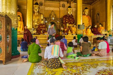 Yangon, Myanmar - 4 Aralık 2012: İnsanlar Yangon tapınağında toplanarak altın heykeller ve canlı dekorasyonlarla çevrili meditasyon ve dua çalışmaları yapıyorlar..