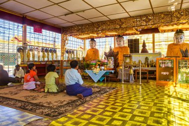 Yangon, Myanmar - 3 Aralık 2012: Dindarlar Yangon 'da dingin bir tapınakta toplandılar ve sessiz bir öğleden sonra Buda heykellerine saygılarını sundular..