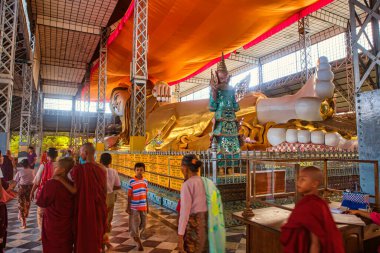 Bago, Myanmar - 3 Aralık 2012: Ziyaretçiler Myanmar 'da büyük bir Buda heykelini gözlemleyen ve dingin atmosferle iç içe geçen bir tapınak keşfettiler.