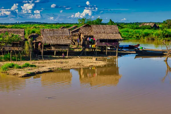 Bago, Myanmar - 03 Aralık 2012: Myanmar 'da yemyeşil ve açık mavi gökyüzü ile çevrili nehir kenarındaki sazlıklar üzerinde köy evleri duruyor.
