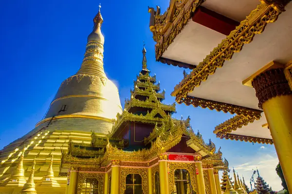 Bago, Myanmar - 03 Aralık 2012: Altın yapılar Myanmar 'daki güneş ışığını yansıtıyor. Myanmar' ın karmaşık mimarisi ve kültürel mirası canlı bir ortamda sergileniyor..